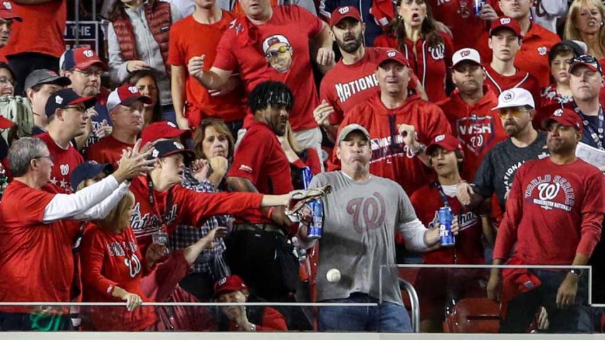 While holding two Bud Light beer cans, baseball fan, Jeff Adams, is hit in the chest with the home run ball hit by Yordan Alvarez #44 of the Houston Astros (not pictured) in the second inning during Game 5 of the 2019 World Series between the Houston Astros and the Washington Nationals at Nationals Park on October 27, 2019 in Washington, DC.