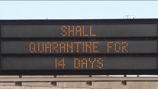 A highway sign urges quarantine for visitors to Maine