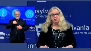 A woman at a podium with a sign language interpreter