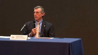 A man seated at a table with a microphone