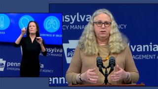 A woman at a podium with a sign language interpreter