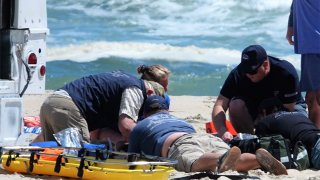 Rescuers work on person on beach