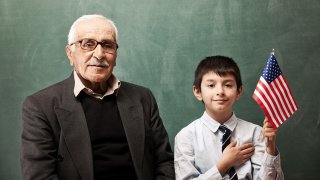 An old man and a young boy pose with the flag