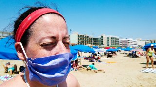 Woman on the beach wearing a mask