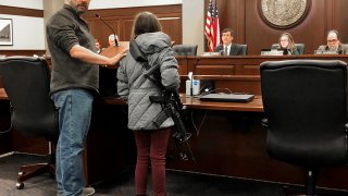 Charles Nielsen, 58, and his 11-year-old granddaughter, Bailey Nielsen, testify before a House panel at the Idaho Statehouse on Monday. Feb. 24, 2020 in Boise, Idaho. Visitors to Idaho 18 and older who can legally possess firearms would be allowed to carry a concealed handgun within city limits under legislation that headed to the House on Monday, Feb. 24. (AP Photo/Keith Ridler)
