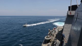 In this Wednesday, April 15, 2020, photo made available by U.S. Navy, Iranian Revolutionary Guard vessels sail close to U.S. military ships in the Persian Gulf near Kuwait.