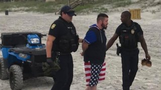 Jacksonville Beach police officers take Mario Matthew Gatti into custody a day after Florida beaches reopen, April 19, 2020. The Pennsylvania homicide suspect, who was caught loitering near the dunes, was wanted for the fatal shooting of 33-year-old Michael Coover, Jr., in January.