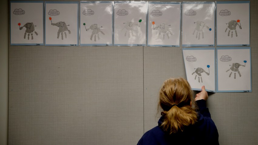 FILE - In this May 12, 2020, file photo, a teacher removes students’ artwork from a bulletin board as she packs the art in her kindergarten classroom at an elementary school in Olathe, Kan.