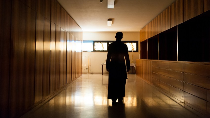 Shadow of young priest dressed in black walking alone in dark mo