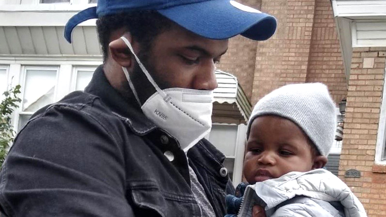 Man wearing face mask holding baby