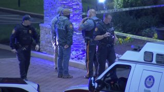 Police in Falls Township, Pennsylvania, stand outside a Holiday Inn Express hotel, where a gunman opened fire and gravely injured a man.
