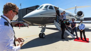 In this April 23, 2020, file photo, members of a delegation of California based-physicians board a waiting Gulfstream IV jet aircraft at the Clay Lacy Aviation terminal, on their way to New York City at Van Nuys Airport in Van Nuys, Calif.