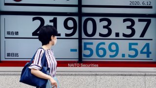 In this June 12, 2020, file photo, a woman looks at an electronic stock board showing Japan's Nikkei 225 index at a securities firm in Tokyo.