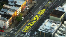 A mural reads "End Racism Now" in yellow letters on a street in Philadelphia's Fishtown neighborhood.