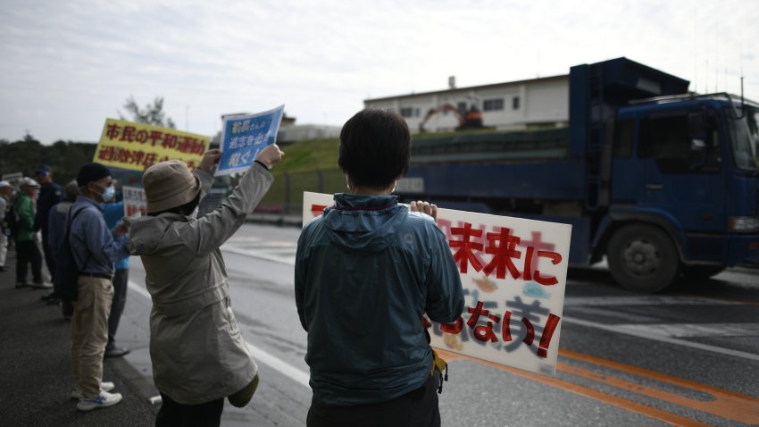 Protesters with placards stand in front of the gate while construction vehicles enters the site during anti U.S. base protest outside of the U.S Base Camp Schwab gate on Feb. 25, 2019, in Nago, Okinawa prefecture, Japan. Based on the prefectural referendum result, more than 70% of voters in Okinawa reject U.S. base transfer in Henoko.