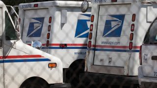 United States Postal Service (USPS) trucks are parked at a postal facility