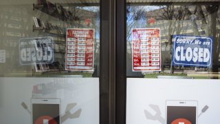 a "Closed" sign hangs in the window of a phone repair shop