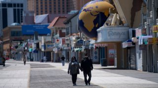 A couple walks on the boardwalk past shuttered stores during the coronavirus pandemic on May 7, 2020 in Atlantic City, New Jersey.