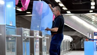 An employee installs plexiglass shields on check-in counters at Sarajevo International Airport on May 19, 2020.