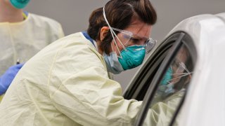 Certified Registered Nurse Kimberly Scheider does a nasal swab on a patient in their car at Penn State Health St. Joseph in Bern Township, Pennsylvania, March 27, 2020.