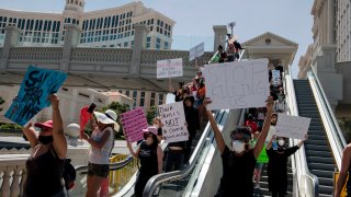 Protestors hold signs and march along the Strip in Las Vegas, Nevada on May 29, 2020, in a demonstration over the death of George Floyd, a black man who died after a white policeman kneeled on his neck for several minutes.