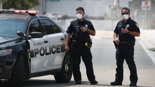 Miami Beach police officers wear protective masks as Florida Gov. Ron DeSantis along with other officials and politicians speak during a press conference at the Miami Beach Convention Center on April 08, 2020 in Miami Beach, Florida. Gov. DeSantis spoke about the U.S. Army Corp. of Engineers converting the convention center into a field hospital with 400 regular hospital beds and 50 ICU beds, with the ability to scale up to 1,000 beds if needed, as the region prepares for a possible surge of coronavirus patients. (Photo by Joe Raedle/Getty Images)