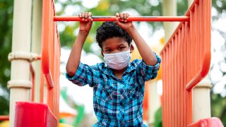 Boy wearing protective face mask while playing at playground.