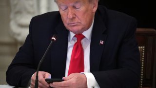 U.S. President Donald Trump looks at his phone during a roundtable at the State Dining Room of the White House June 18, 2020 in Washington, DC.