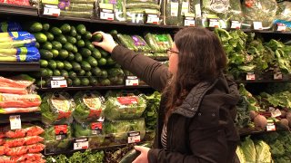 Woman picking produce in a grocery store