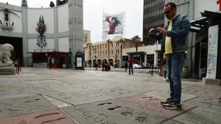 A man takes a picture of the hand and footprints of actor Tom Hanks in the forecourt of the TCL Chinese Theatre