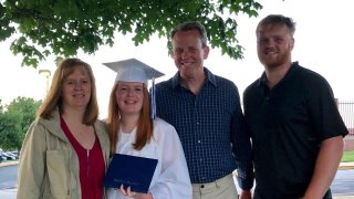 family posing with girl in graduation cap and gown