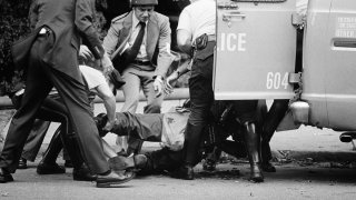 Officers lift gunshot victim James Ramp into police van after he was shot during confrontation with radical group "MOVE" Tuesday morning, August 8, 1978 in Philadelphia's west side.