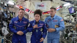 astronaut Jessica Meir speaks, accompanied by Andrew Morgan and Chris Cassidy,