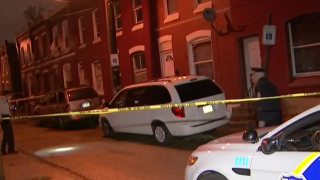 A police cruiser and police tape surround a van in front of a home in North Philadelphia, where a man was shot.