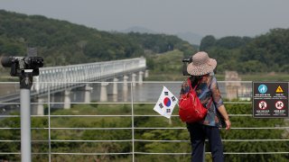 A visitor carrying a South Korean flag uses binoculars to view the northern side at the Imjingak Pavilion in Paju, South Korea, Tuesday, June 9, 2020.