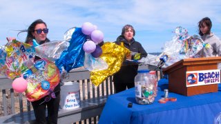 In this April 2, 2019, file photo, Lisa Cordova, left, Cindy Zipf, center and Alison McCarthy, right, of the Clean Ocean Action environmental group, unfurl a banner made of balloons they picked up from the beach at Sandy Hook N.J.