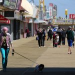 A woman with pink hair walks her dog through the arcade area on the newly rebuilt boardwalk