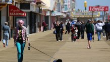 A woman with pink hair walks her dog through the arcade area on the newly rebuilt boardwalk