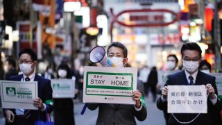 Staff of the Tokyo Metropolitan Government urge people to go home from the Kabukicho entertainment district in the Shinjuku Ward on the evening in Tokyo Friday, April 24, 2020. Japan’s Prime Minister Shinzo Abe expanded a state of emergency to all of Japan from just Tokyo and other urban areas as the virus continues to spread.