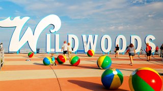 The Wildwoods sign in Wildwood, New Jersey with people walking in front of it.