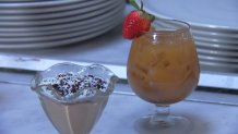 A brown cocktail with a strawberry next to a chocolate dessert in a glass.