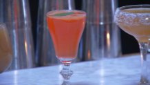 A red cocktail sitting on a bar top.