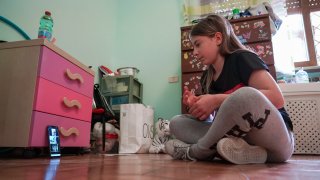 In May 14, 2020, file photo, Elena Moretti looks at her cellphone as she prepares to attend an online dancing lesson, in her bedroom in Rome. For the 11-year-old, the COVID-19 coronavirus pandemic is not some faraway threat: Italy was the first European country to be hit by COVID-19, and her mother is a doctor in the public health system that has seen 25,000 personnel infected and more than 160 doctors dead nationwide.
