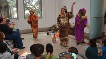 Women dancing in outfits from African culture in front of a crowd of children.