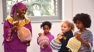 A woman and children play instruments from African culture.