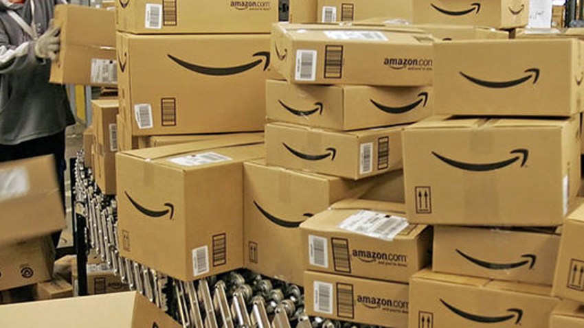 In this Dec. 13, 2005, file photo, Amazon.com worker David Brendoff, left, moves boxes with merchandise for shipment at the Amazon.com fulfillment center in Fernley, Nevada.