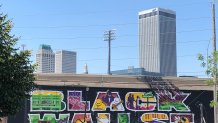 Black Wall Street mural with downtown Tulsa in the background.