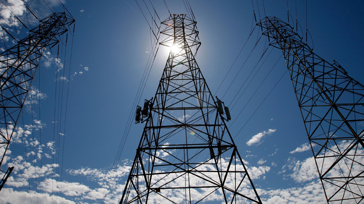 The sun shines over towers carrying electical lines.