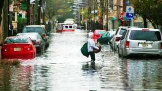 A resident walks through flood water and past a stalled ambulance in the aftermath of superstorm Sandy on Tuesday, Oct. 30, 2012 in Hoboken, NJ.