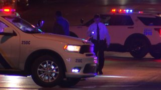 Philadelphia police officers stand behind highway patrol cruisers as they investigate a high-speed chase following a drive-by shooting in Philadelphia.